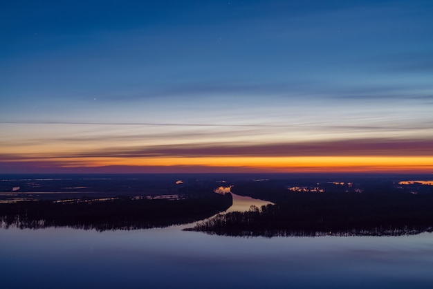 Beautiful river with big island with trees under predawn sky.