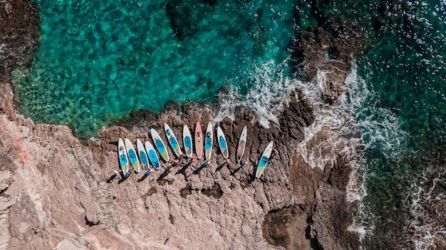 Photo beautiful rocky beach with sup stand up paddle boards and with turquoise water in montenegro view from above with drone