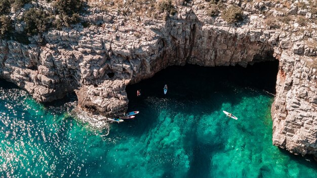 Photo beautiful rocky beach with sup stand up paddle boards and with turquoise water in montenegro view from above with drone