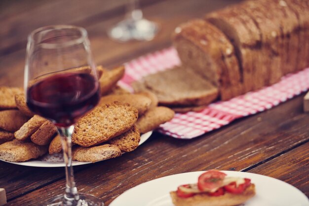 Photo beautiful romantic composition with a glass of red wine and toasted bread on wooden table