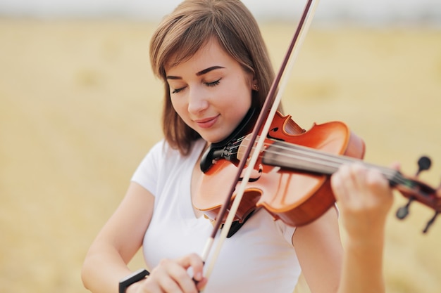 사진 수확 후 필드에서 바이올린을 연주 느슨한 머리를 가진 아름다운 낭만적 인 소녀