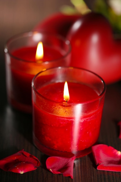 Beautiful romantic red candles with flower petals on dark wooden background