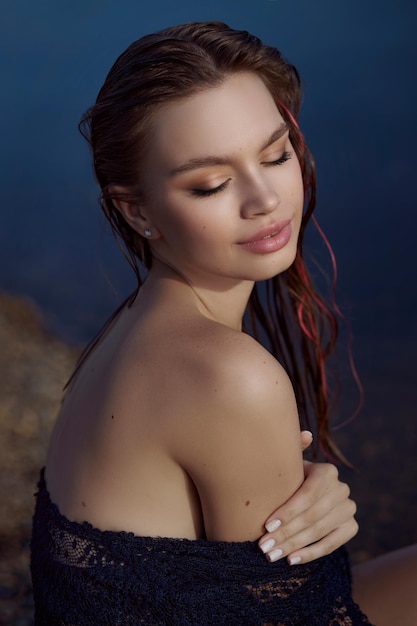 Beautiful romantic woman sitting near a pond lake Wet woman in her underwear in the rays of the sun at sunset Natural beauty long hair