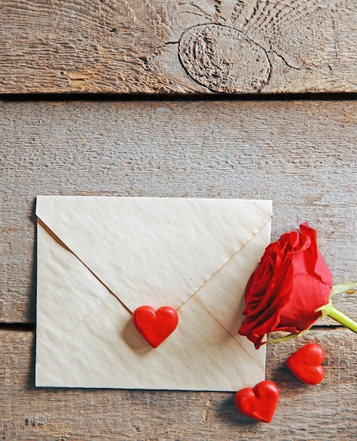 Beautiful rose with gift card on wooden background