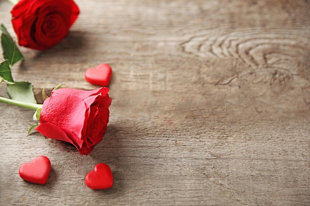 Beautiful rose with small hearts on wooden background