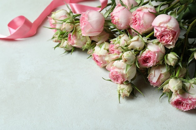 Beautiful roses and pink ribbon on white textured