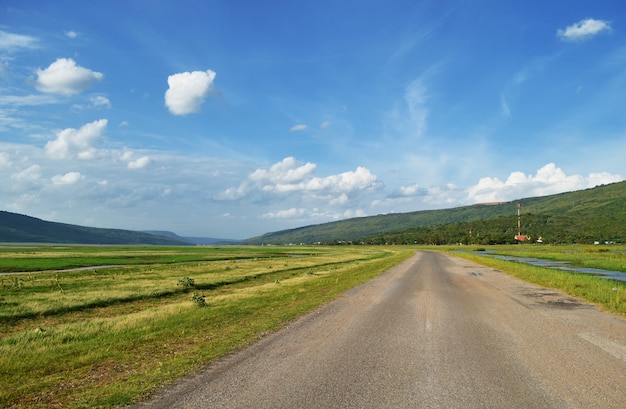 Beautiful rural road and blue sky between rural field.