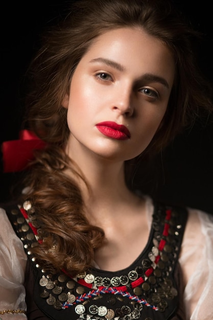編みこみの髪型と赤い唇を持つ民族衣装の美しいロシアの女の子美顔