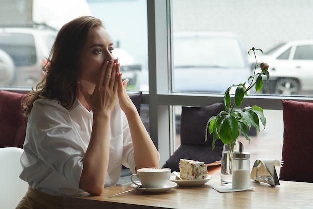 カフェで一人で座っている美しい悲しい女性。カフェの奥深くに悲しい若い女性。彼女は悲しいです。