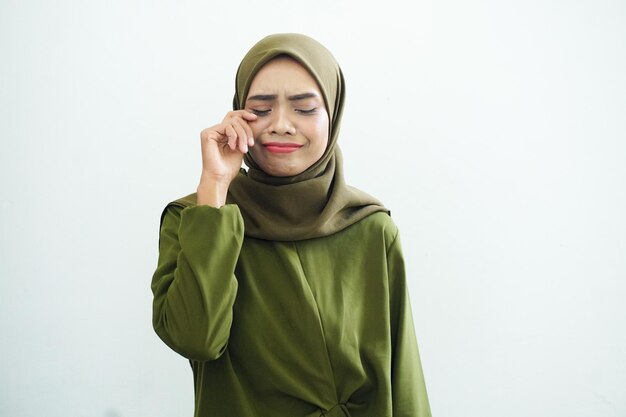 緑のドレスと目を保持しているヒジャブを身に着けている美しい悲しい若いアジアのイスラム教徒の女性