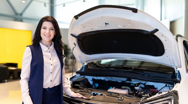 Beautiful sale-manger inspect new car in dealership showroom