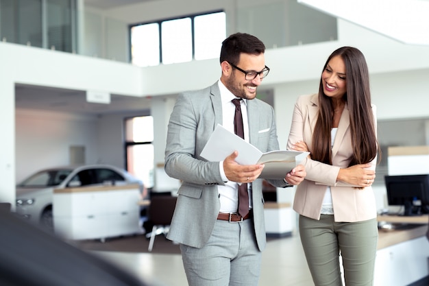 Beautiful saleswoman presenting cars to a customer