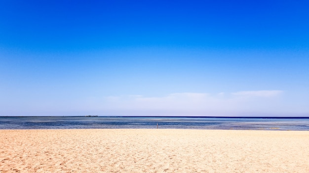 A beautiful sandy beach without people and a tropical blue sea with blue sky background.