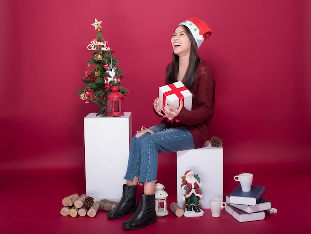 Beautiful Santa Claus girl in studio on red background, Christmas concept