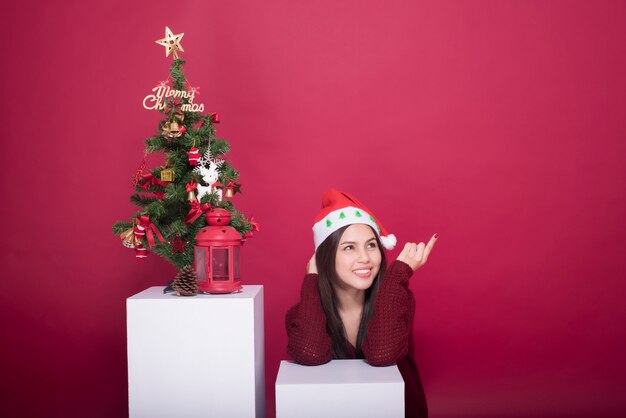 Beautiful Santa Claus girl in studio on red background, Christmas concept