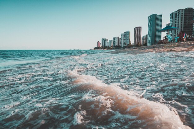 Beautiful scenery of the sea waves splashing on the beach in Ondas with buildings in the background