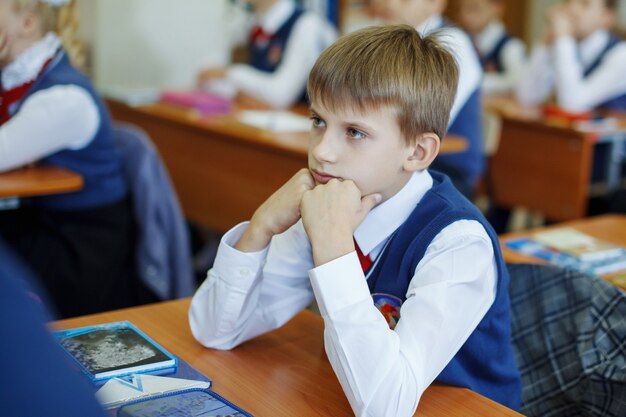 Beautiful school child at a desk on a holiday. Gets education in primary school