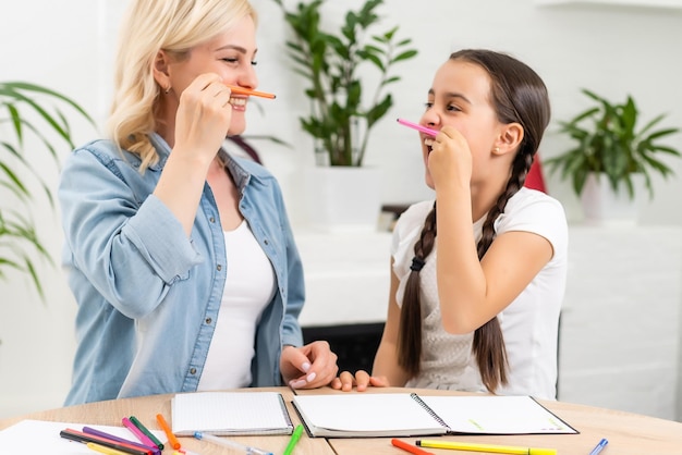 Beautiful school girl doing homework with mother at home.