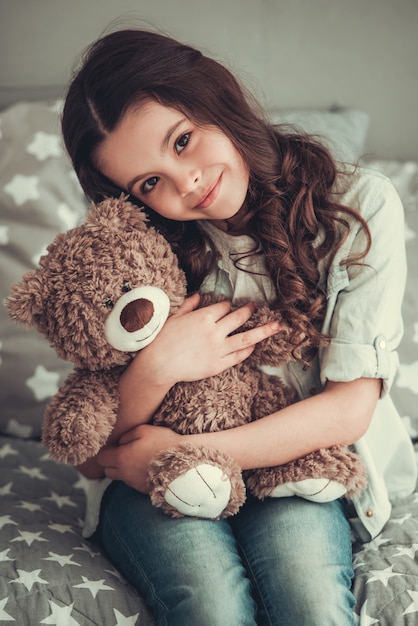 Photo beautiful school girl is hugging a teddy bear.