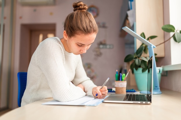 Beautiful schoolgirl studying at home doing school homework