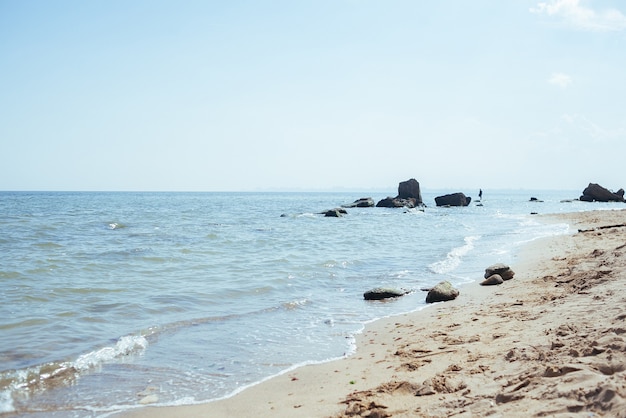 写真 夏の正午の美しい海、澄んだ水、砂浜。静かな波は真昼の太陽に照らされています。