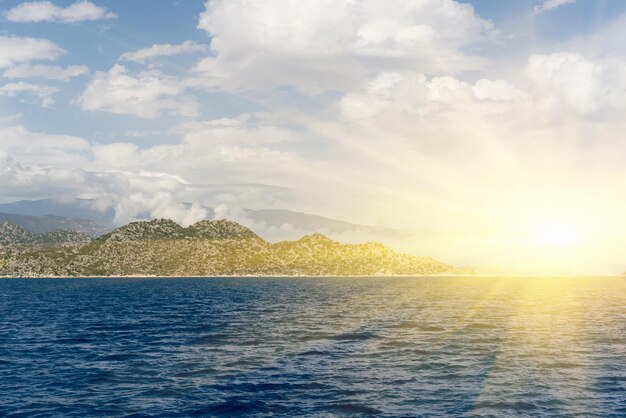 Beautiful seascape calm water rocks and cloudy sky in the sunlight