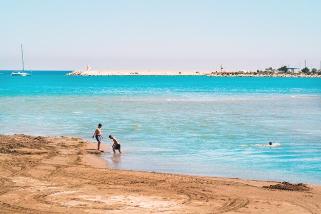 Beautiful seascape sandy beach and people swiming in the blue sea