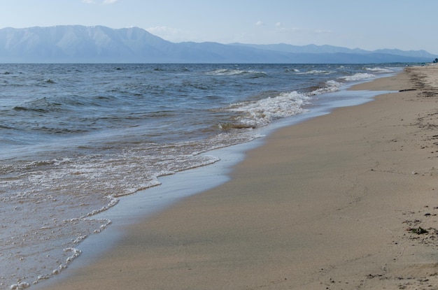 Bellissimo paesaggio marino le onde del lago baikal bagnano la costa sabbiosa