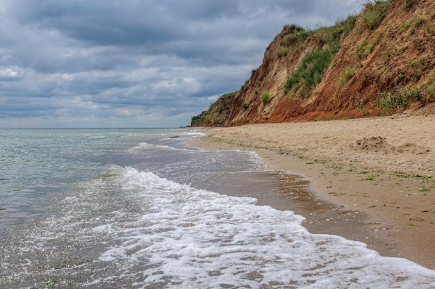 Foto un bellissimo paesaggio marino con una ripida costa di argilla rossa e un bel cielo