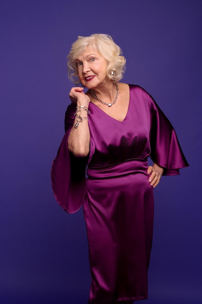 Beautiful senior blonde woman in an evening violet dress looking enjoyed