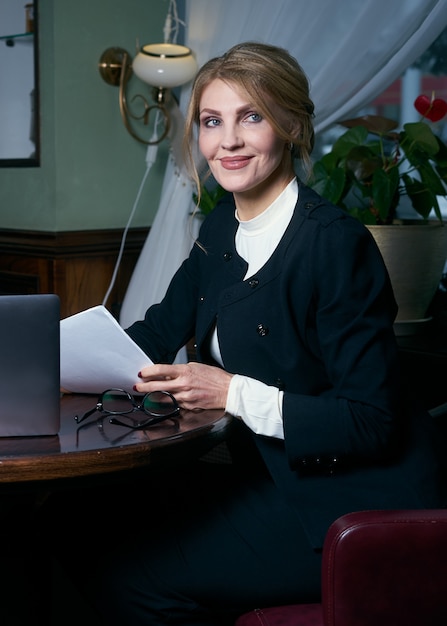 Photo beautiful senior businesswoman working in cafe with laptop and notepad