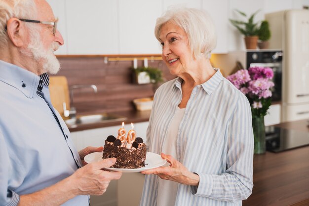 Beautiful senior couple celebrating  anniversary with birthday cake - Elderly couple having birthday party at home