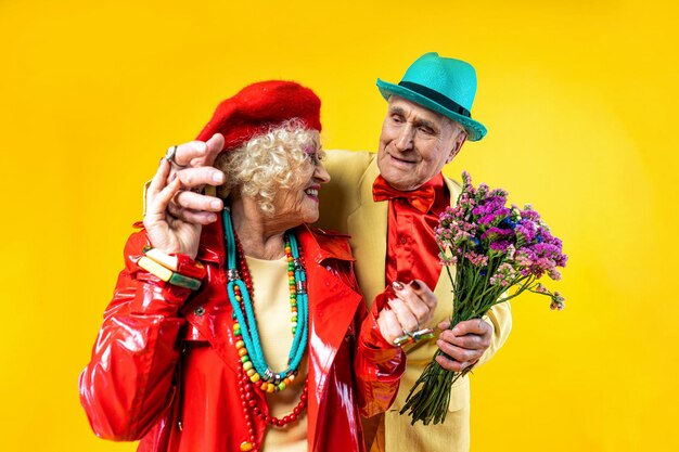 Beautiful senior old couple wearing fancy party clothes acting in studio on a colored background conceptual image about third age and seniority old people feeling young inside