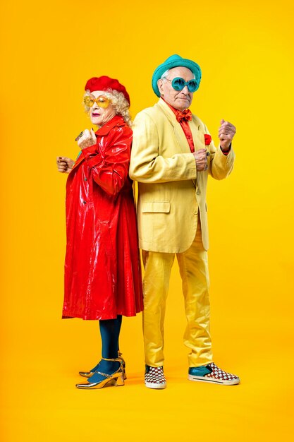 Beautiful senior old couple wearing fancy party clothes acting in studio on a colored background conceptual image about third age and seniority old people feeling young inside