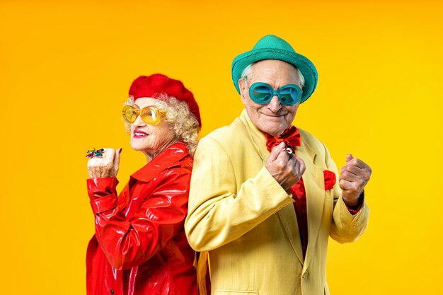 Beautiful senior old couple wearing fancy party clothes acting in studio on a colored background conceptual image about third age and seniority old people feeling young inside