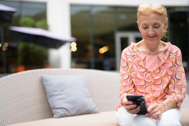 Beautiful senior tourist woman with blond hair relaxing on sofa