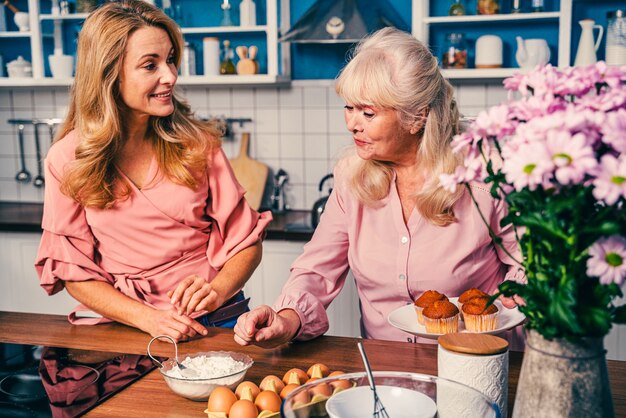 Beautiful senior woman and daughter baking in the kitchen