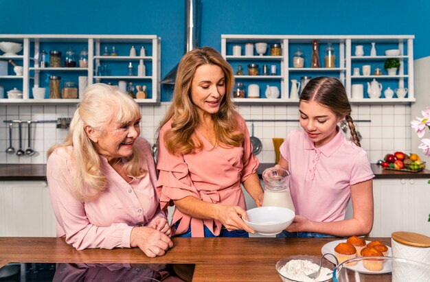 Beautiful senior woman and family baking in the kitchen  Grandmother preparing desserts at home with daughter and nephew concepts about cooking and healthy eating