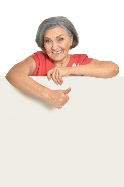 Beautiful senior woman in pink dress holding blank banner isolated on white background