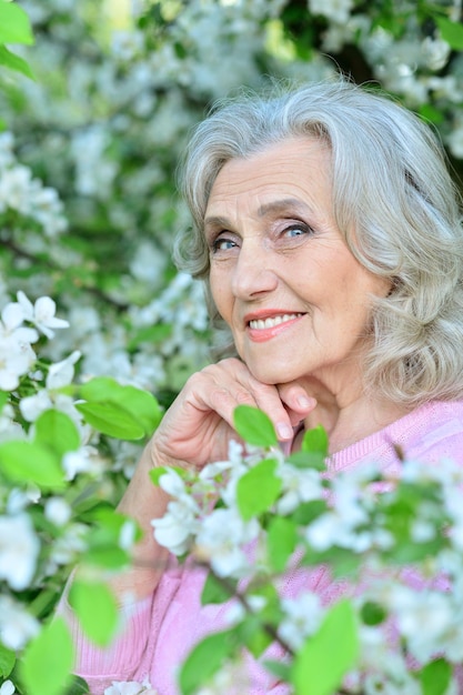 Beautiful senior woman posing near blooming tree