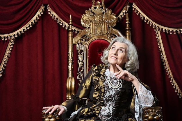 Beautiful senior woman Queen posing on throne