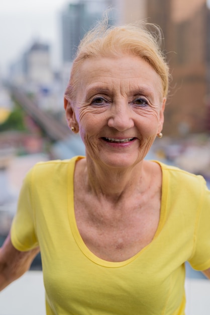 Красивая старшая женщина улыбается на открытом воздухе в городе