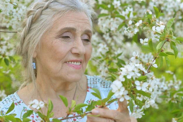 Beautiful senior woman standing near blooming tree