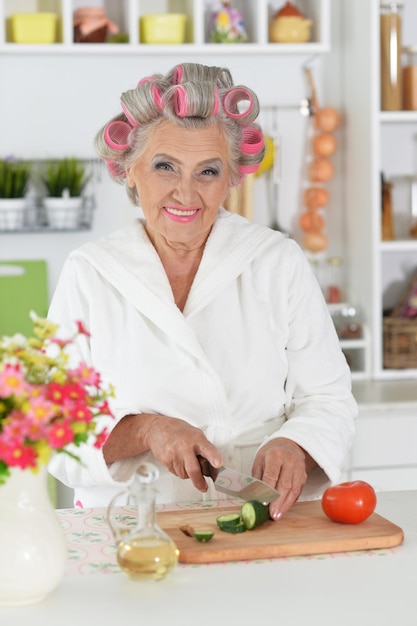 Beautiful senior woman wearing white bathrobe and hair curlers