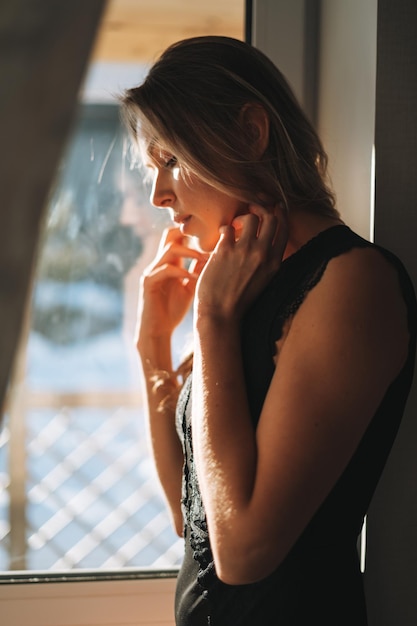 Photo beautiful sensual blonde young woman in underwear near window with hard light at home