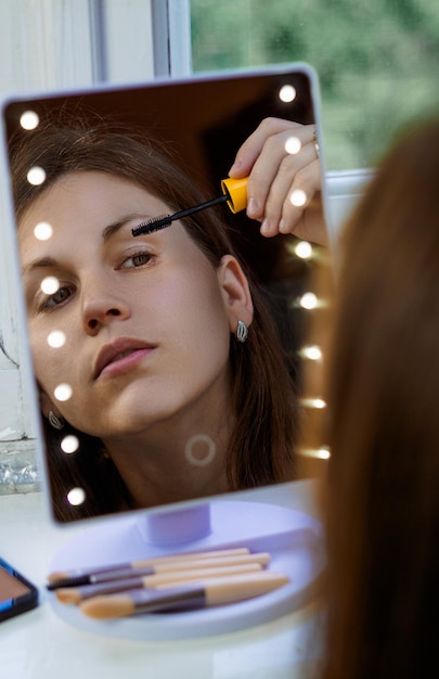 beautiful and sensual woman putting on makeup in a mirror