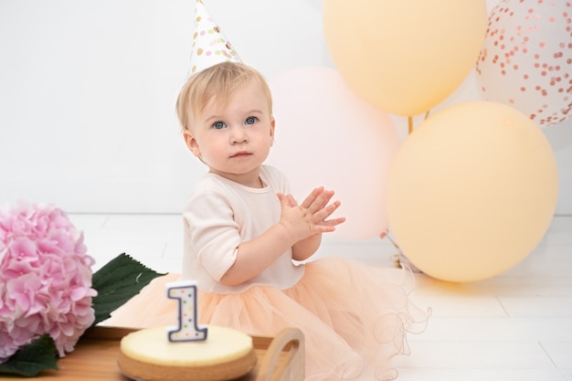 Beautiful serious caucasian blond infant girl celebrating first year birthdaylooking at camera