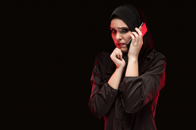 助けを求めて黒ヒジャーブを着て美しい深刻なおびえた若いイスラム教徒の女性