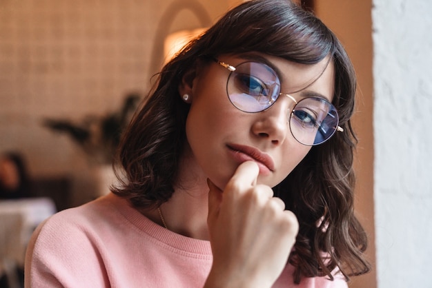 a beautiful serious woman indoors in cafe looking.