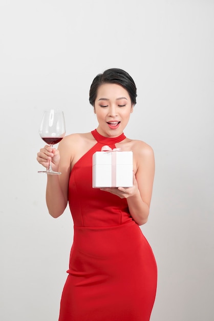 ギフト用の箱とシャンパン グラスを持って、笑っている美しいセクシーなアジアの女の子